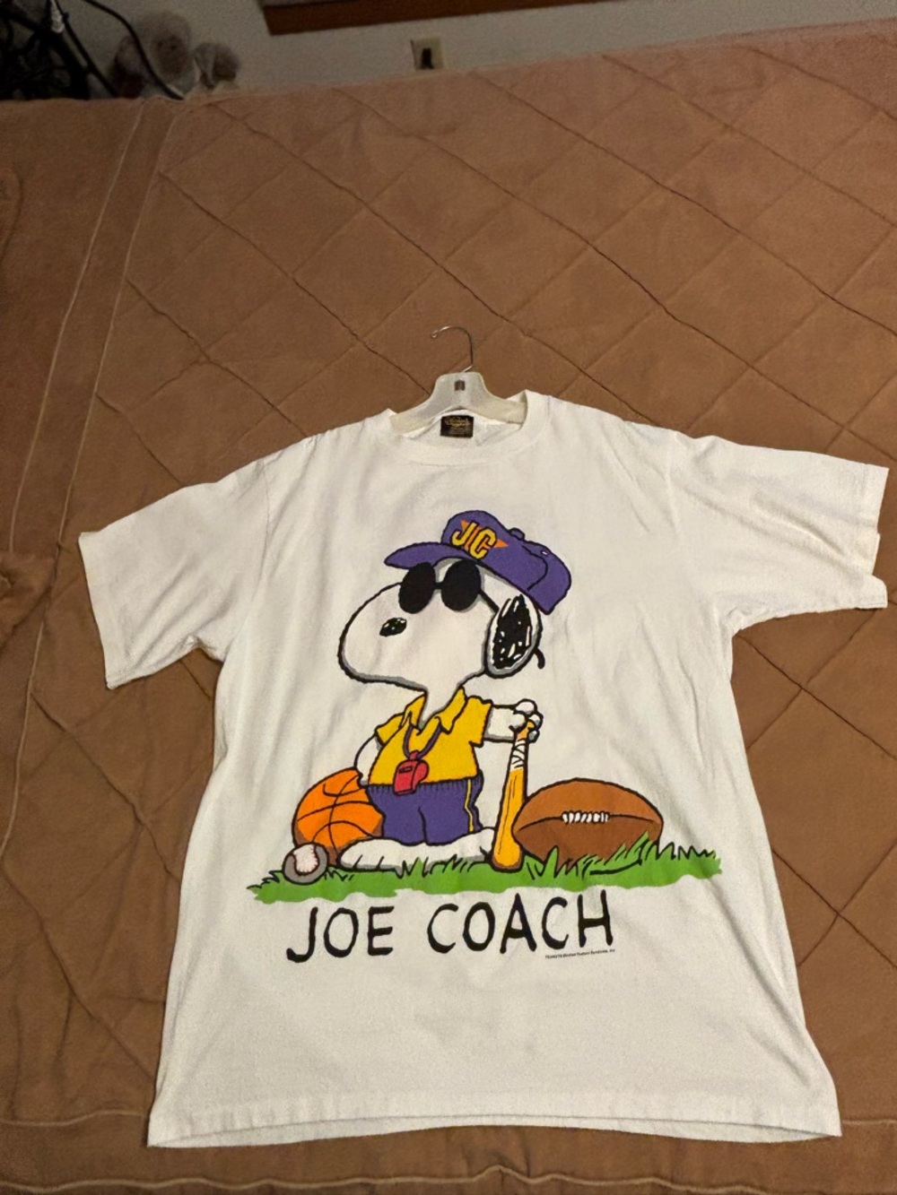 Peanuts White T-Shirt with Purple, Yellow and Black Snoopy Coach Graphic.